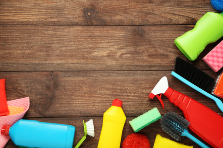 Bottles with detergent and cleaning tools on wooden tableの写真素材