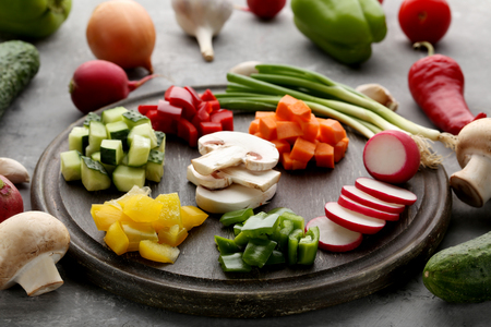 Fresh sliced vegetables on brown cutting boardの写真素材