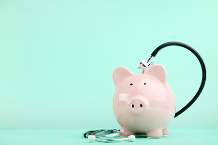 Pink piggy bank with stethoscope on mint backgroundの写真素材
