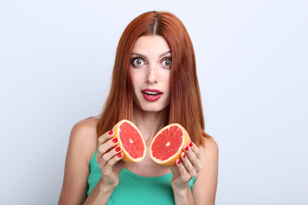 Beautiful redhaired woman with grapefruit on grey backgroundの写真素材