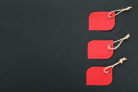 Red sale tags on black background