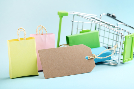 Small paper shopping bags with shopping cart on blue backgroundの写真素材
