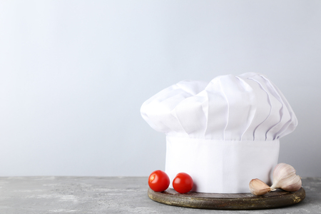 Chef hat with tomatoes and garlic on grey wooden tableの写真素材