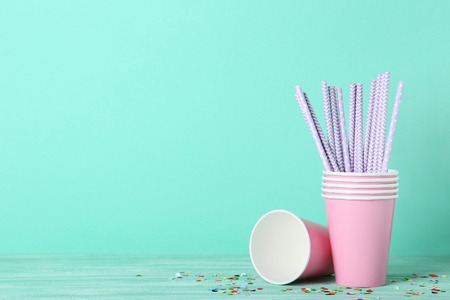 Pink paper cups with straws on mint background