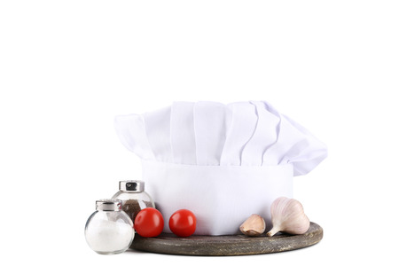 Chef hat with salt, pepper and vegetables on white backgroundの写真素材