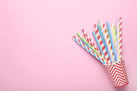 Red paper cup with colorful straws on pink background