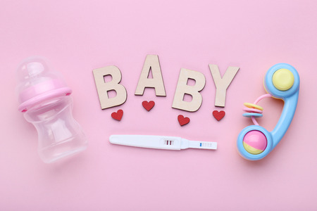 Pregnancy test with little bottle and toy on pink backgroundの写真素材