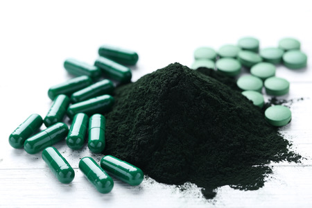 Spirulina powder and tablets on white wooden tableの写真素材