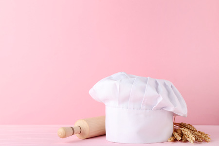 Chef hat with rolling pin and wheat ears on pink backgroundの写真素材