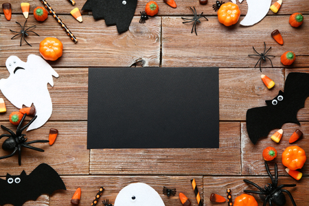 Blank paper with halloween candies and paper decorations on wooden tableの写真素材