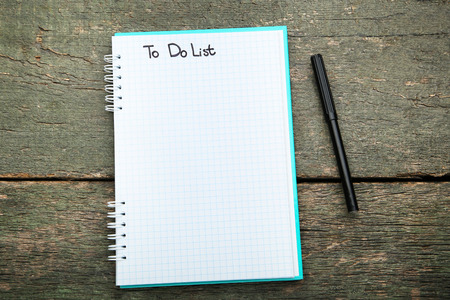 To do list in notepad with felt-tip pen on grey wooden tableの写真素材