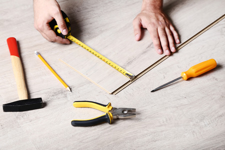 Man installing timber laminate flooring with toolsの写真素材