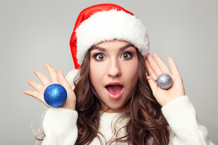 Young woman in santa hat with baubles on grey backgroundの写真素材