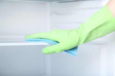 Hand in glove with sponge cleaning refrigerator