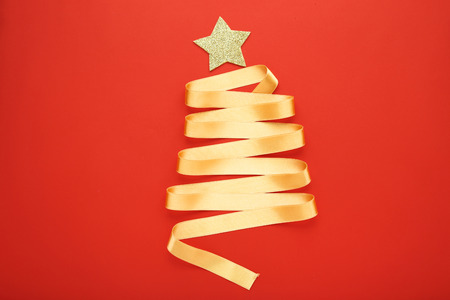 Golden ribbon in shape of christmas tree on red backgroundの写真素材