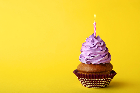 Tasty cupcake with candle on yellow backgroundの写真素材