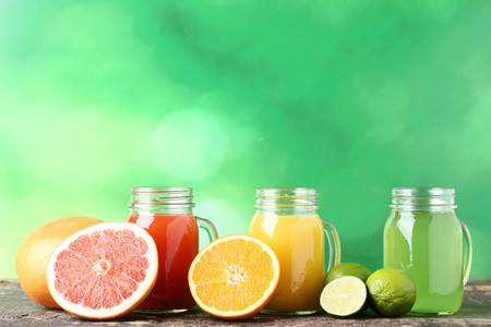 Citrus juice in glass jars with fruits on green backgroundの写真素材