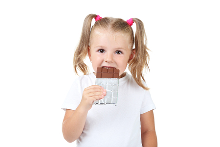 Happy little girl eating chocolate on white backgroundの写真素材