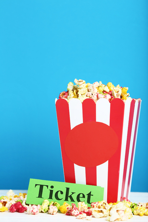 Colorful popcorn in striped bucket on blue backgroundの写真素材