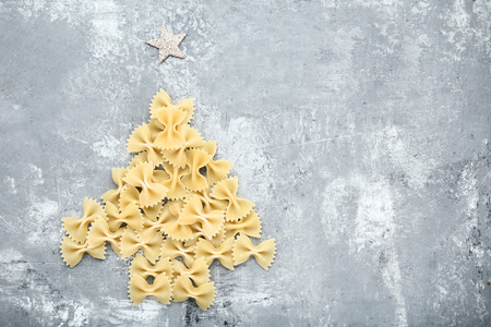 Bow tie pasta in shape of christmas tree on grey wooden tableの写真素材