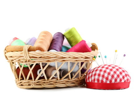 Colored threads in basket with pincushion on white backgroundの写真素材
