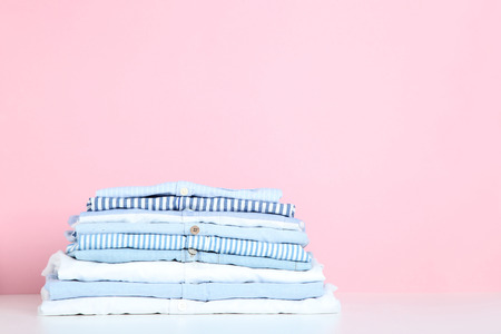 Stack of folded shirts on pink backgroundの写真素材