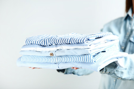 Female hands holding folded shirtsの写真素材