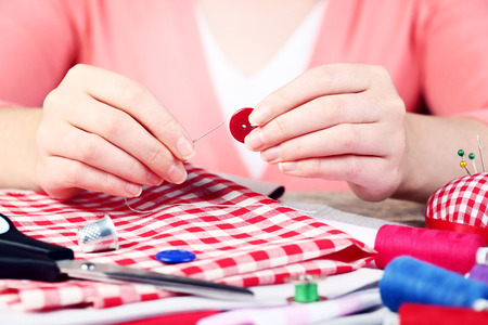 Female hands sewing button