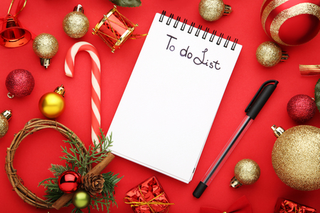 To do list in notepad with christmas decorations on red backgroundの写真素材