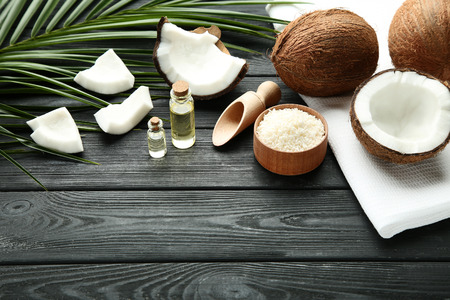 Coconuts with oil in bottles and flakes on wooden tableの写真素材
