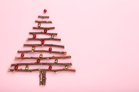 Tree branches in shape of christmas tree with baubles on pink backgroundの写真素材