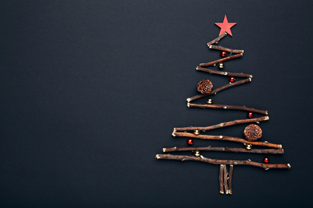 Tree branches in shape of christmas tree with baubles and cones on black backgroundの写真素材