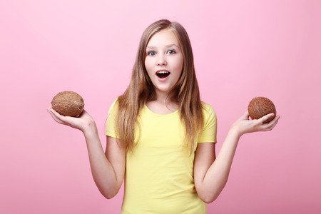 Cute young girl with coconuts on pink backgroundの写真素材
