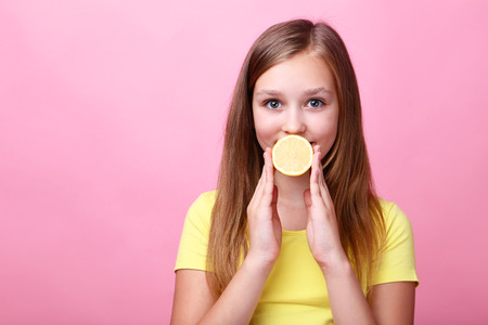Cute young girl with lemon on pink backgroundの写真素材