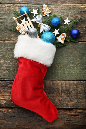 Red stocking with fir-tree branches and christmas decorations on wooden tableの写真素材