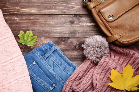 Clothes with leather bag and maple leafs on brown wooden tableの写真素材