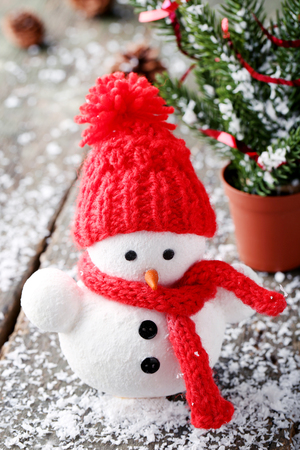 Small snowman toy with fir-tree branches on wooden tableの写真素材