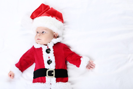 Baby boy in christmas costume lying on bedの写真素材
