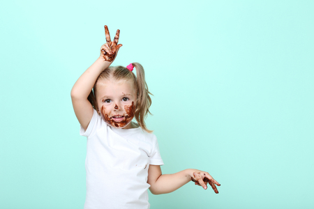 Happy little girl in chocolate on mint backgroundの写真素材