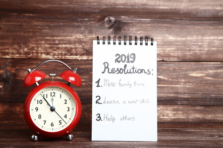 Inscription 2019 resolutions in notepad with red alarm clockの写真素材