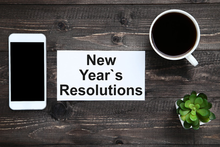 New year resolutions on sheet of paper with smartphone and cup of coffeeの写真素材