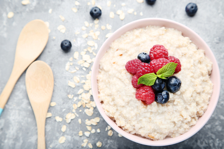 Oatmeal with berries in bowl on grey wooden tableの写真素材