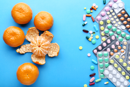 Mandarin fruits and colorful pills on blue backgroundの写真素材