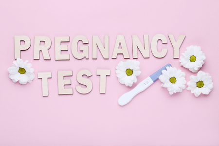 Pregnancy test with chrysanthemum flowers on pink backgroundの写真素材