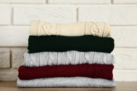 Stack of folded sweaters on brick wall background