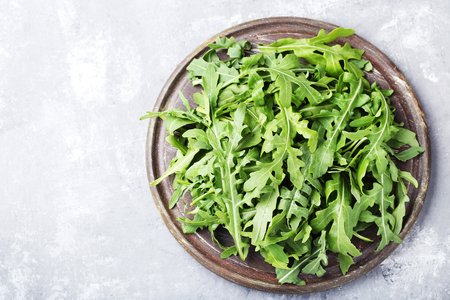 Green arugula leafs on wooden cutting boardの写真素材