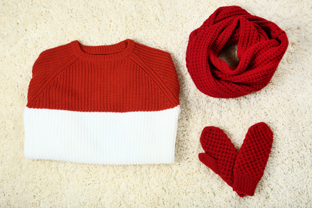 Folded sweater with scarf and gloves on white carpetの写真素材