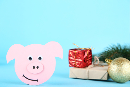 Paper pig with gift boxes and bauble on blue backgroundの写真素材