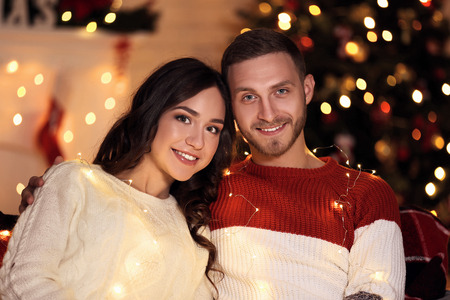 Happy young couple sitting at home near christmas treeの写真素材