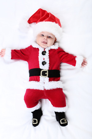 Baby boy in christmas costume lying on bedの写真素材